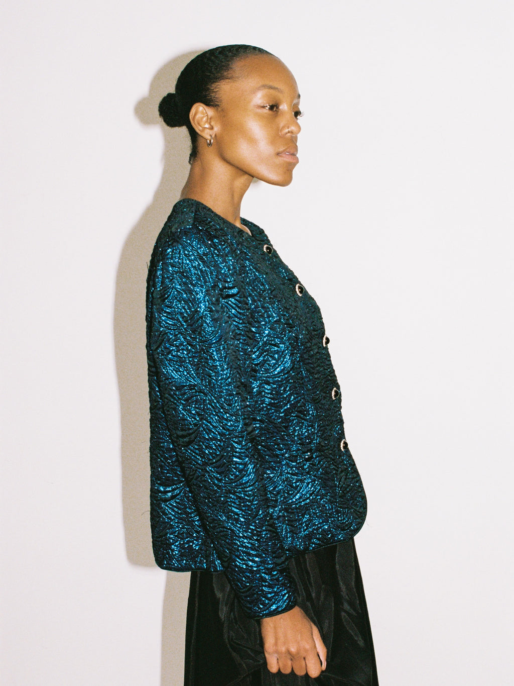 Woman wearing a blue textured jacket against a white background