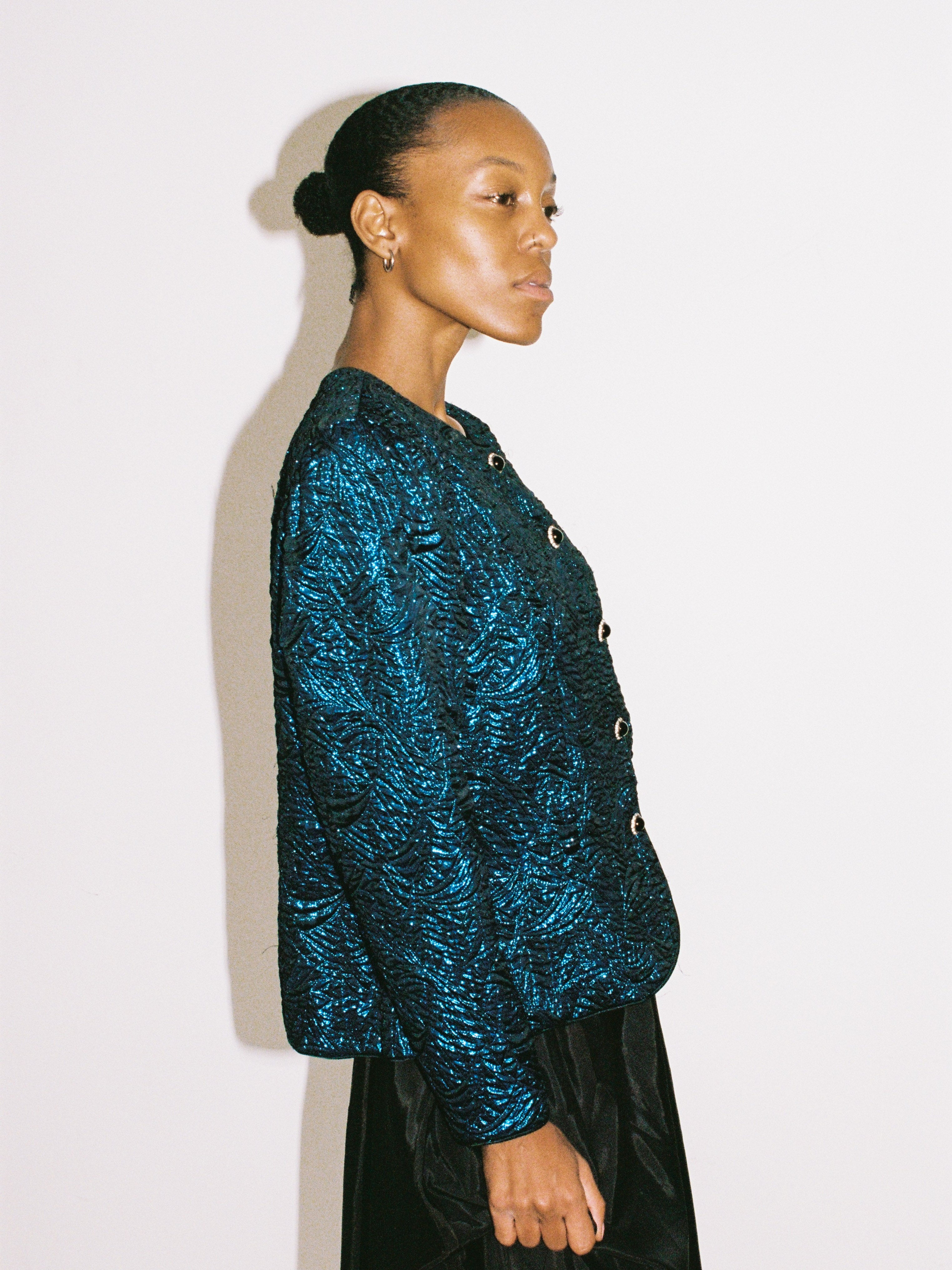 Woman wearing a blue textured jacket against a white background