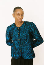 Person wearing a blue patterned jacket against a white background