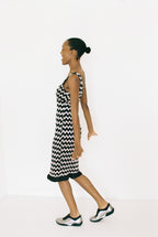 Woman wearing a black and white zigzag dress on a white background