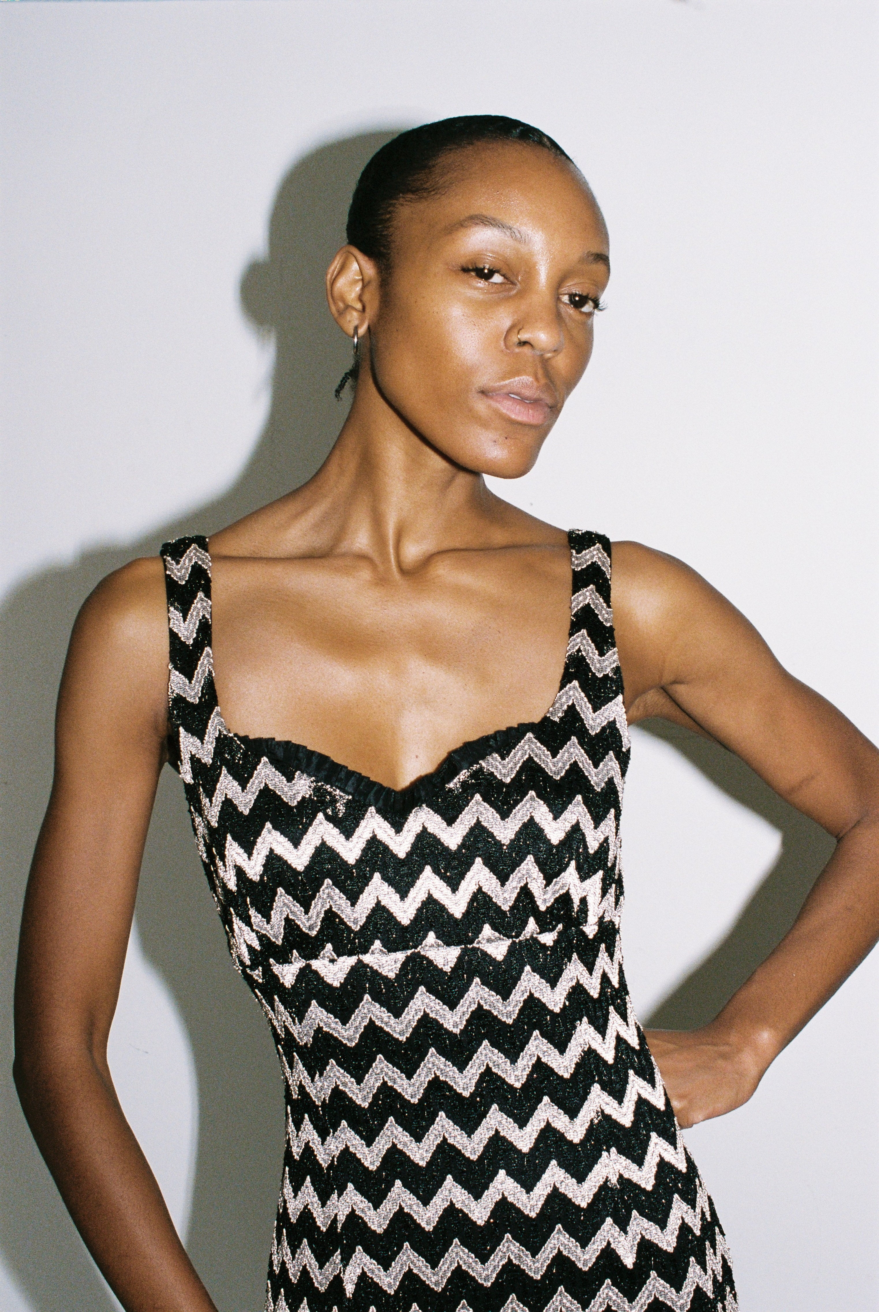 Woman wearing a black and silver zigzag patterned dress against a plain background
