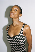Woman wearing a black and silver zigzag patterned dress against a plain background