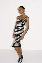 Woman wearing a black and silver zigzag dress against a white background