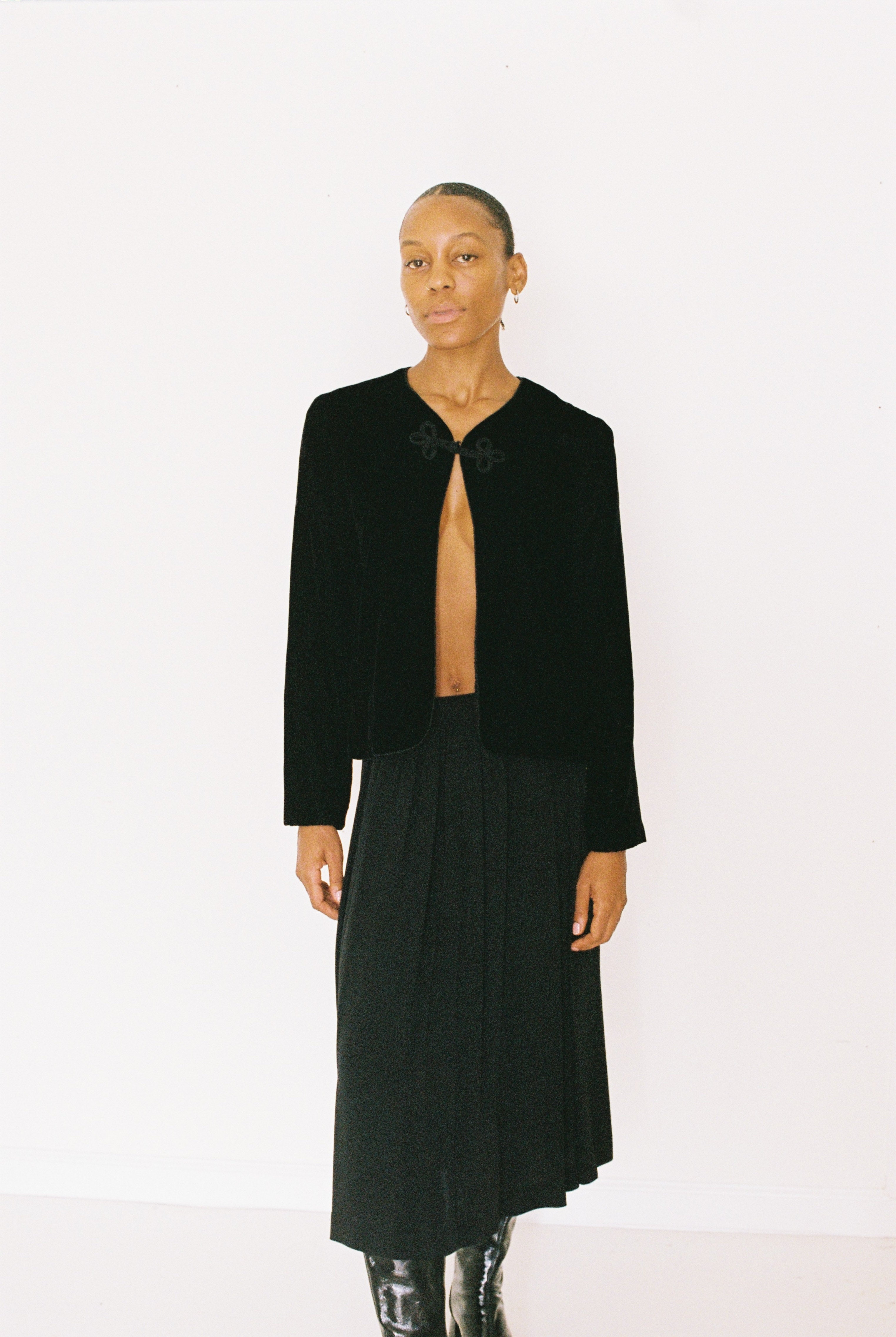 Person wearing a black jacket and skirt on a white background