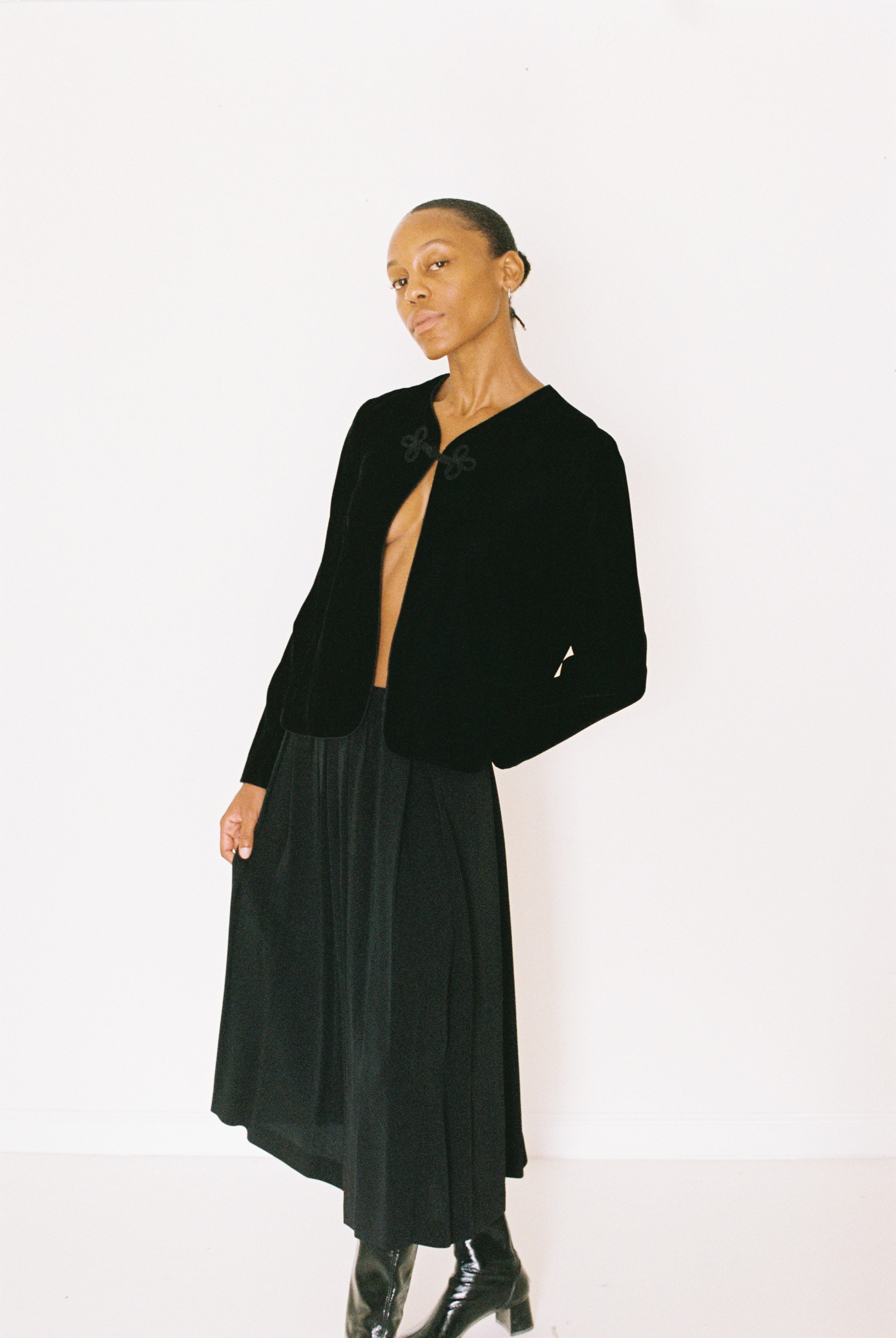 Person wearing a black velvet jacket and skirt on a white background