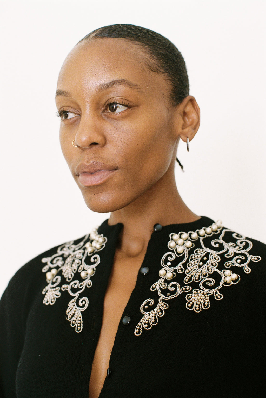 Woman wearing a black top with intricate white embroidery on a white background