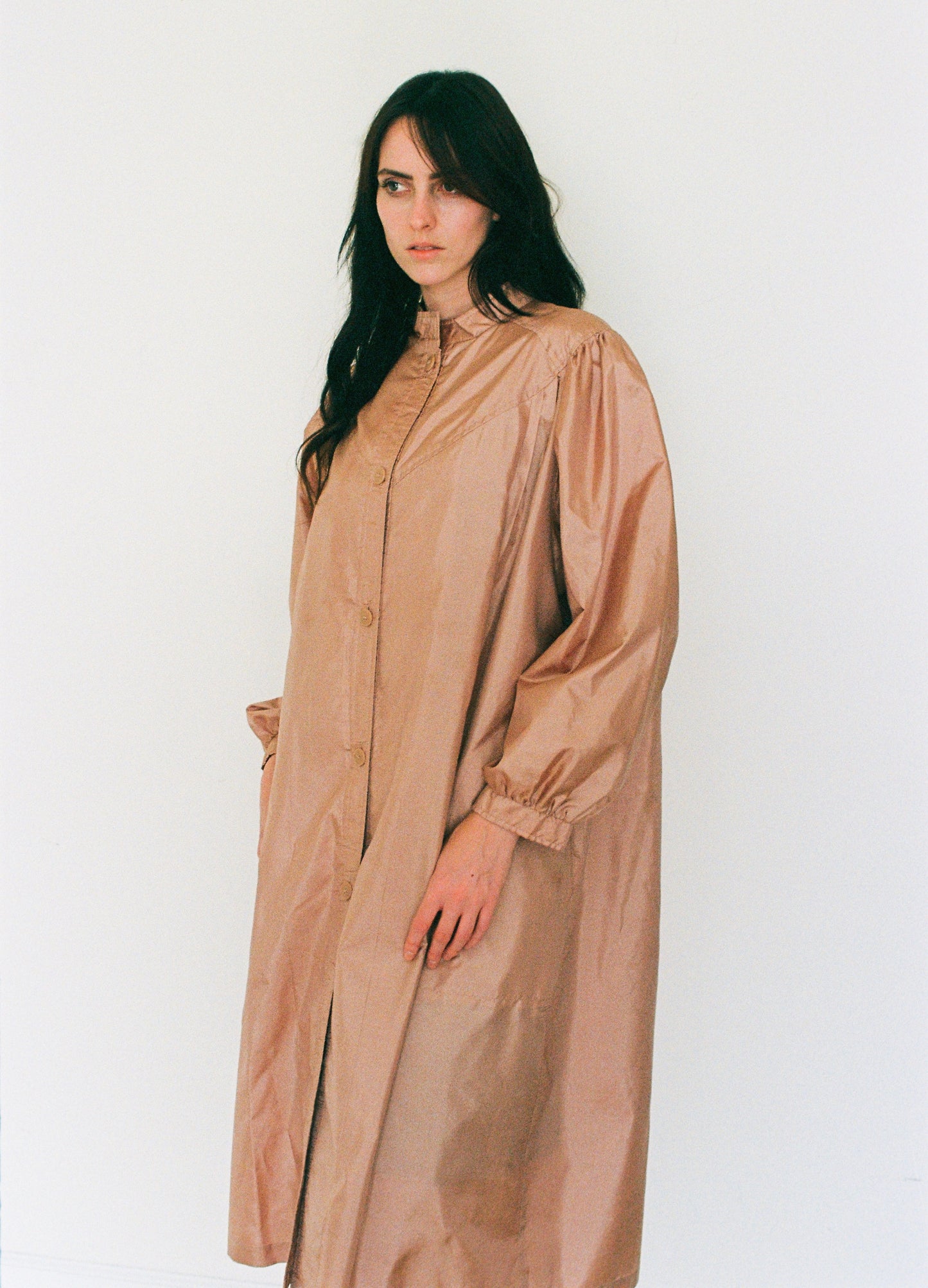 Woman wearing a long beige dress against a white background