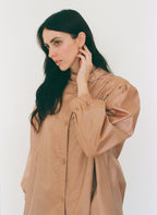 Woman wearing a brown blouse against a white background