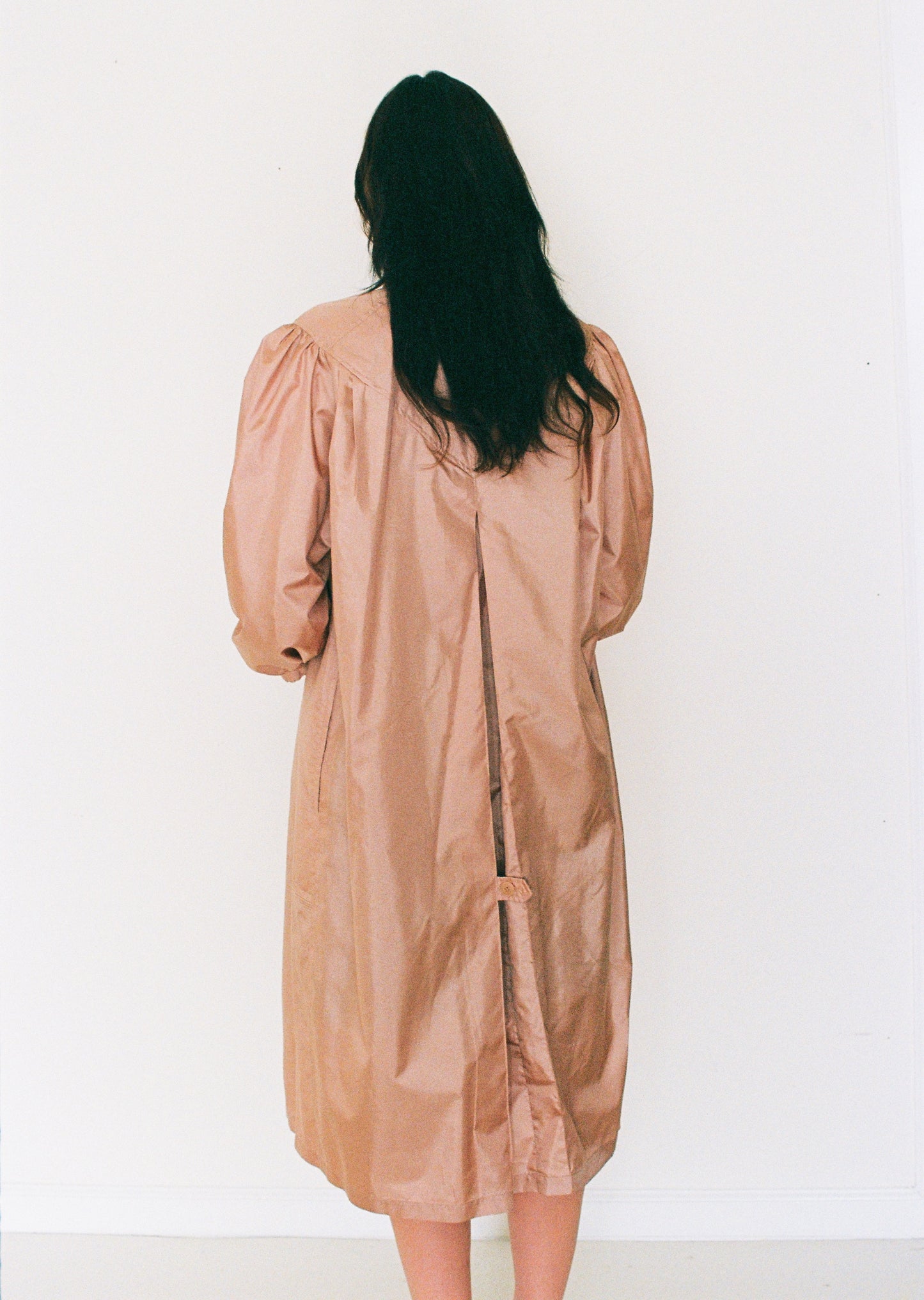 Person wearing a beige dress against a white background