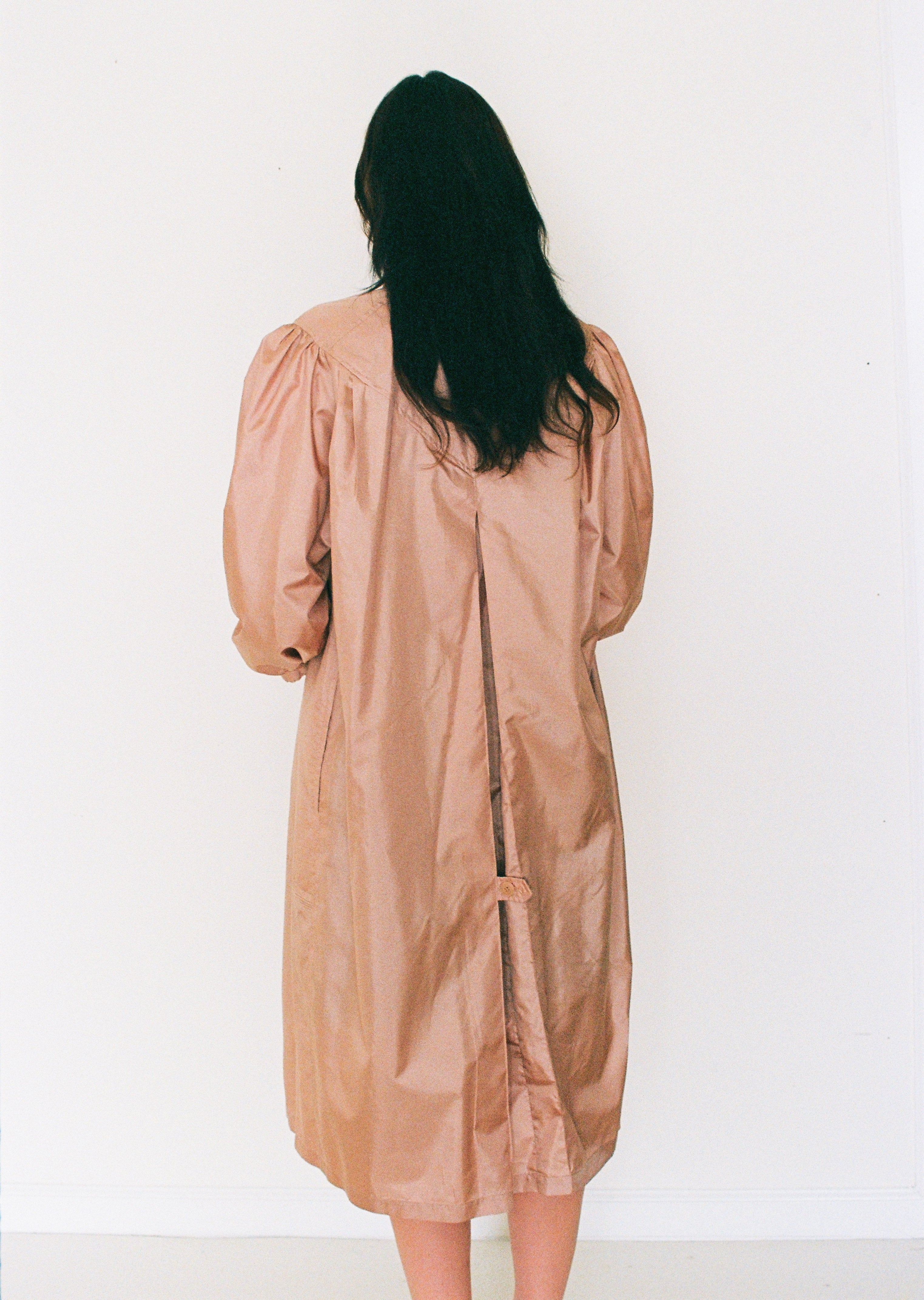 Person wearing a beige dress against a white background