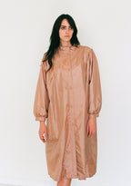 Woman wearing a beige raincoat against a white background