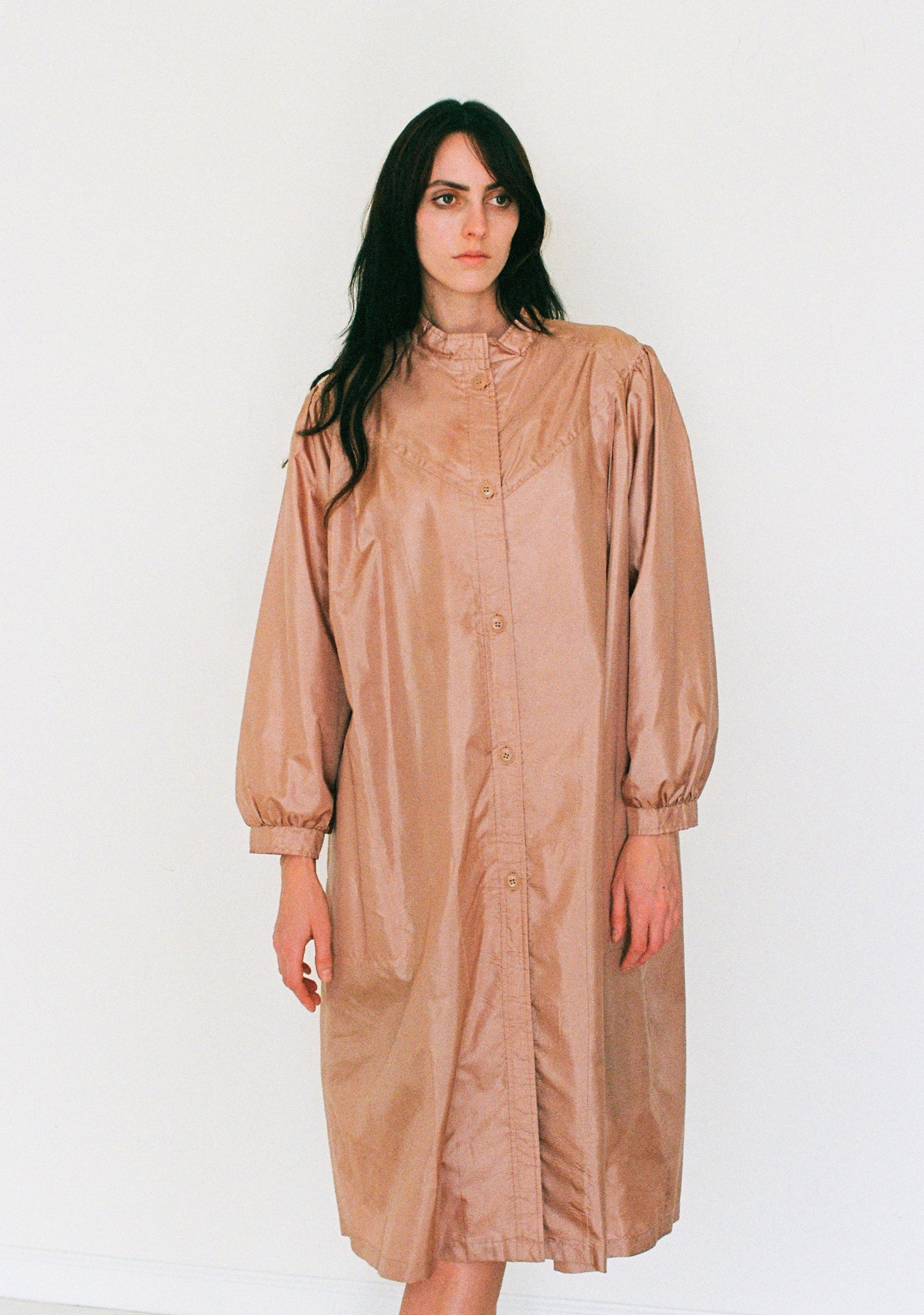 Woman wearing a beige raincoat against a white background