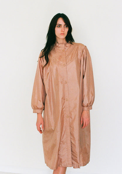 Woman wearing a beige raincoat against a white background