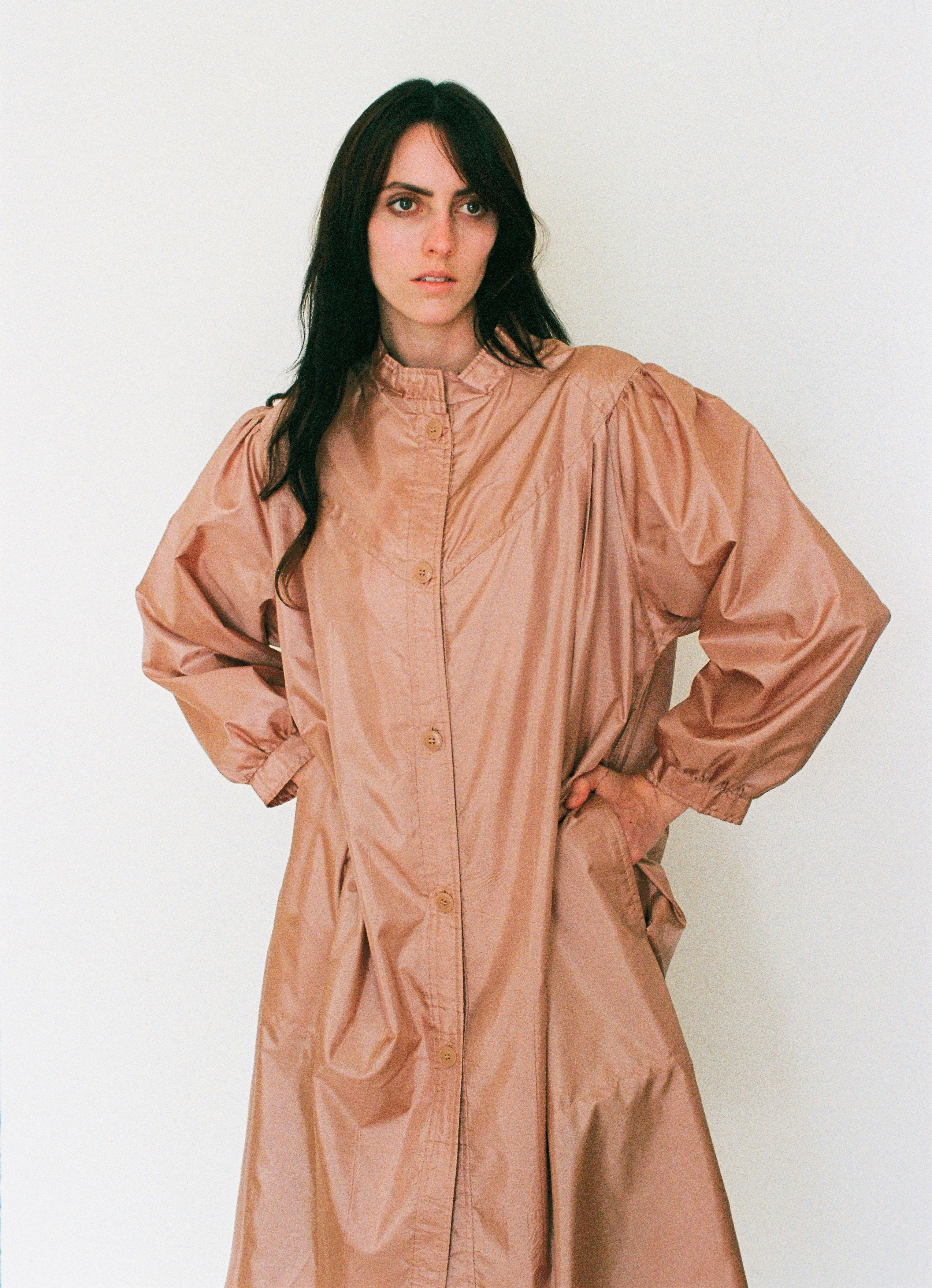 Woman wearing a long beige coat against a white background