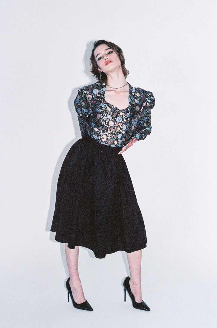 Woman wearing a floral blouse and black skirt against a white background