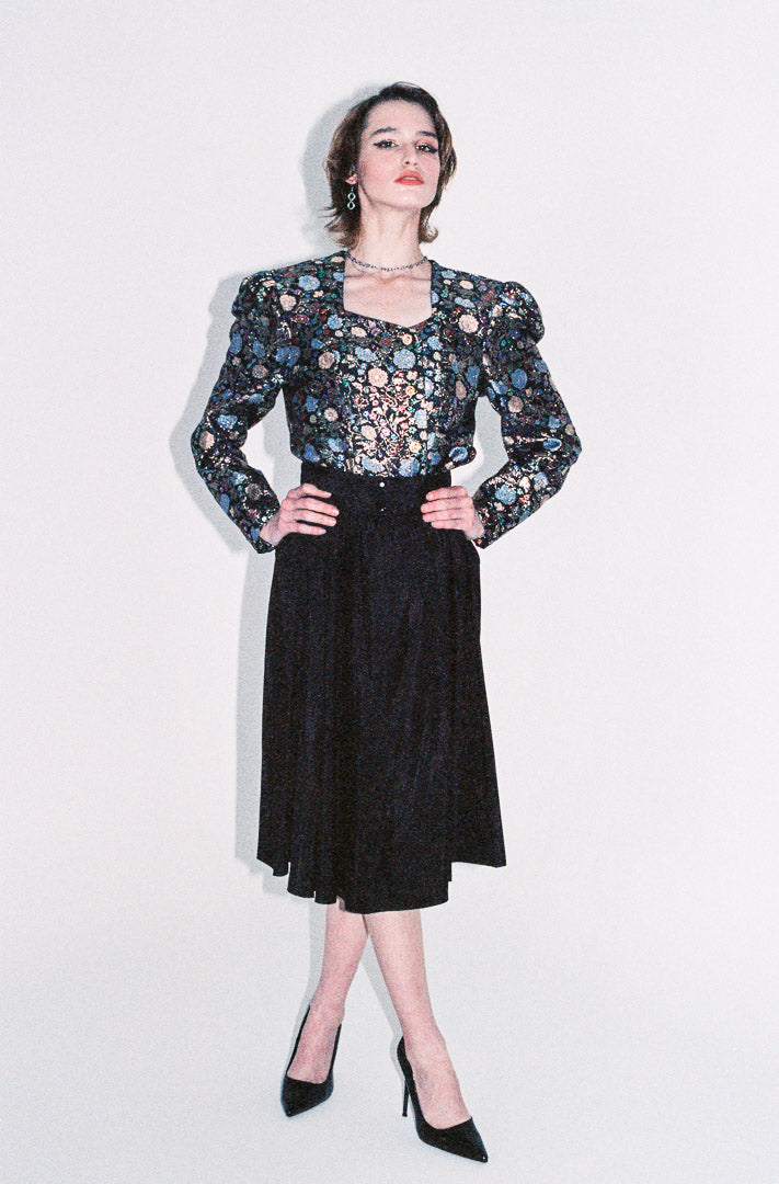 Woman wearing a floral blouse and black skirt on a white background
