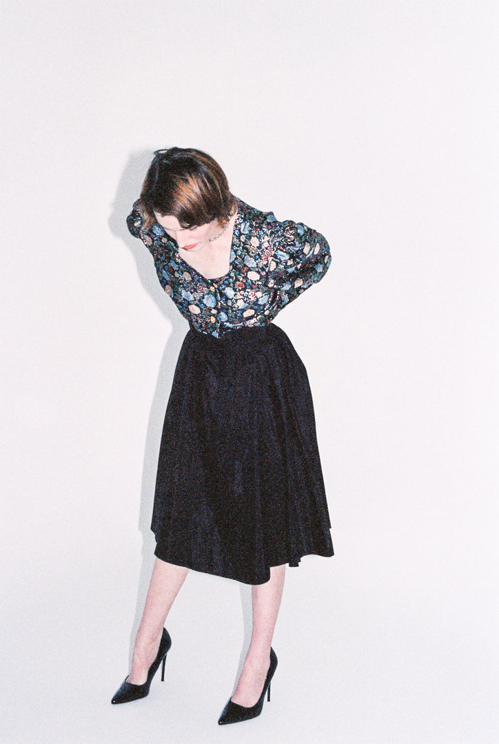 Person wearing a floral blouse and black skirt on a white background