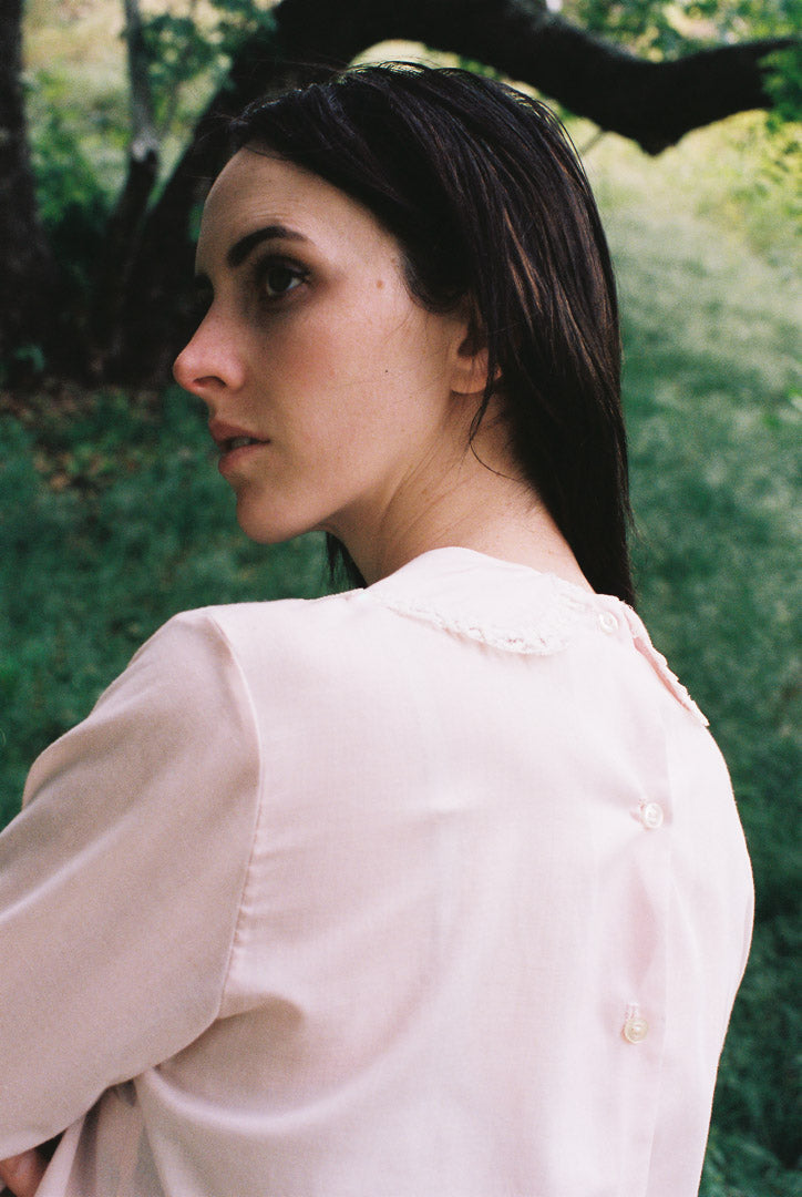 Woman wearing a light-colored blouse in a natural setting