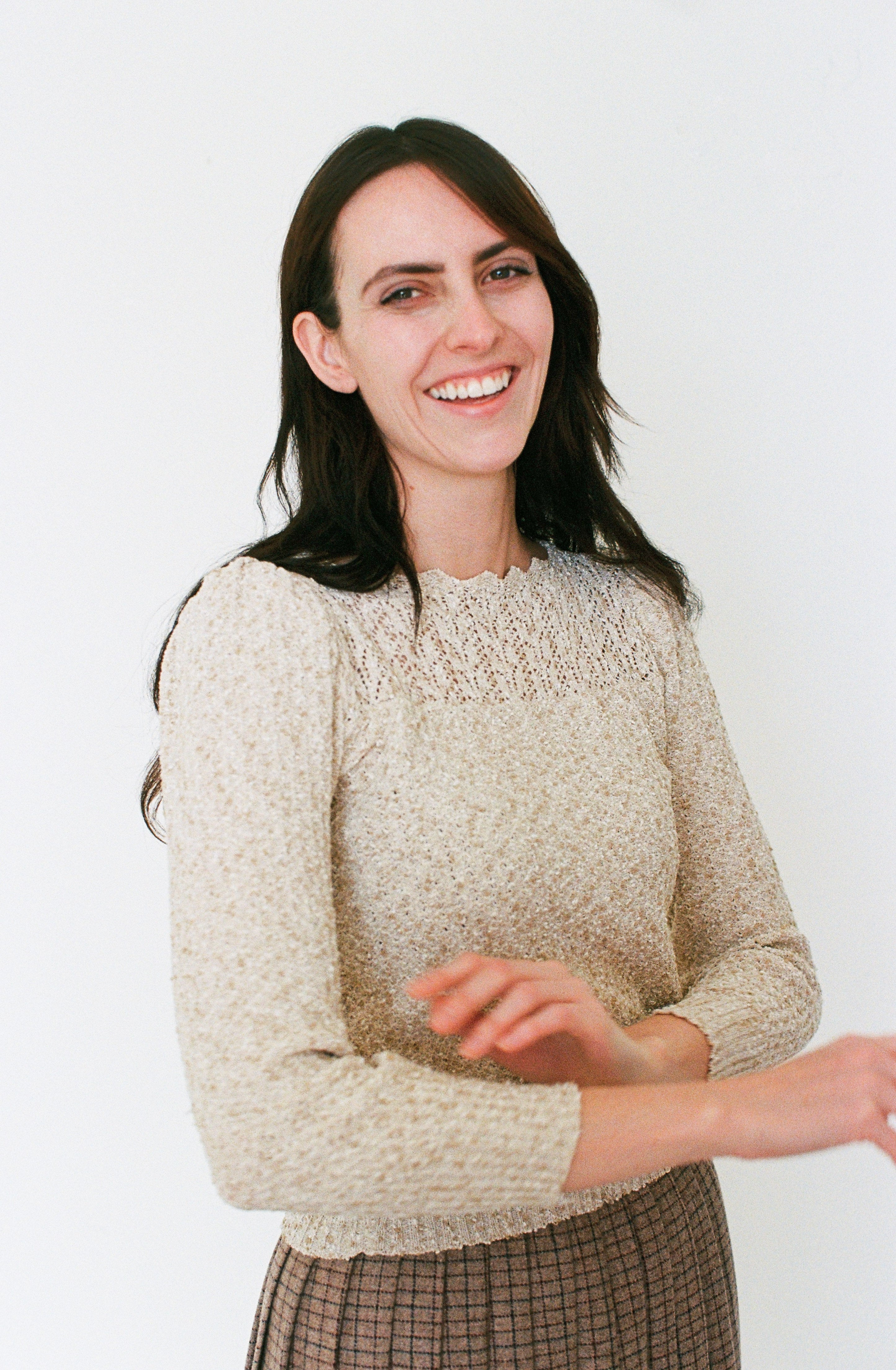 Woman wearing a beige sweater against a white background