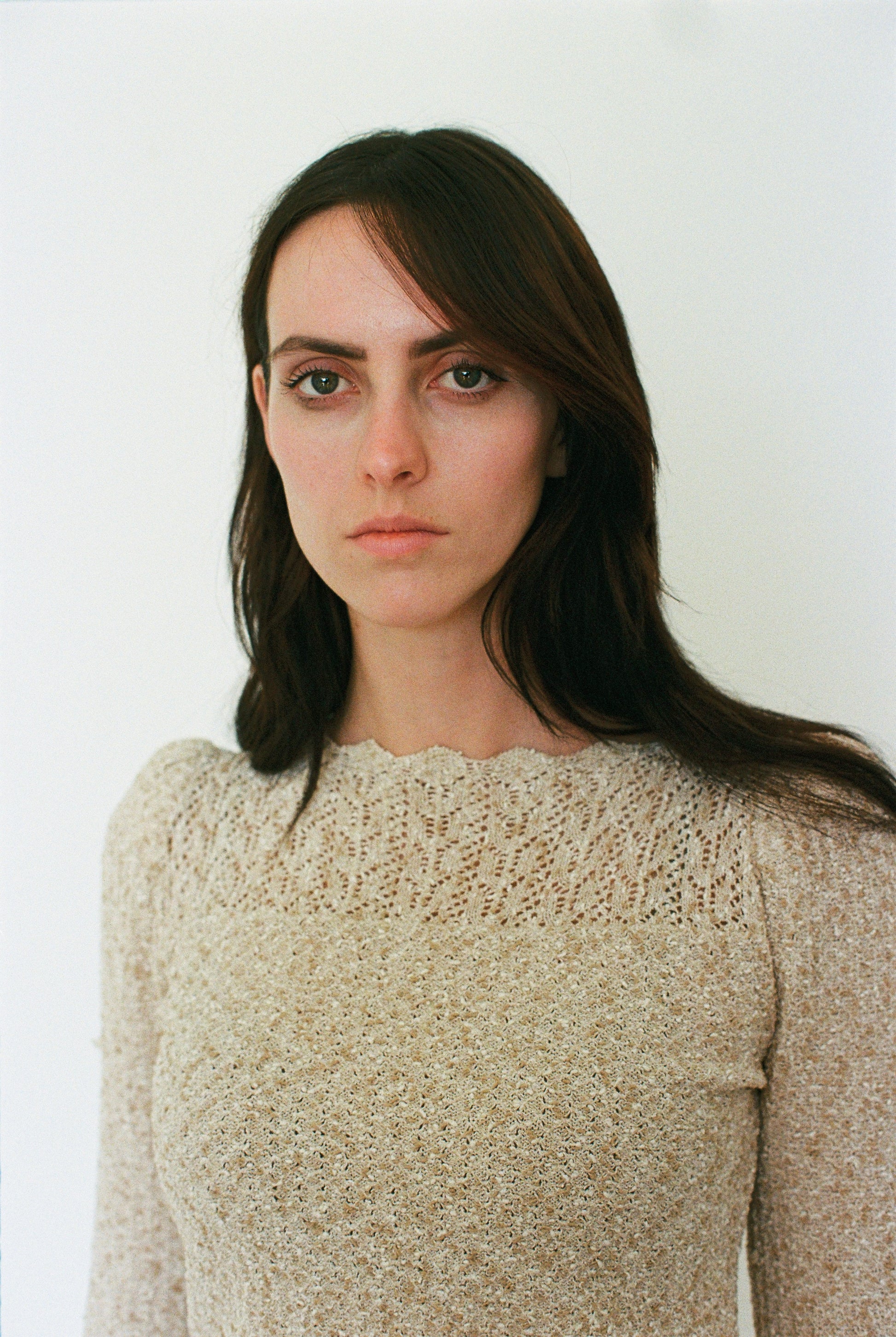 Woman wearing a beige knitted sweater against a white background