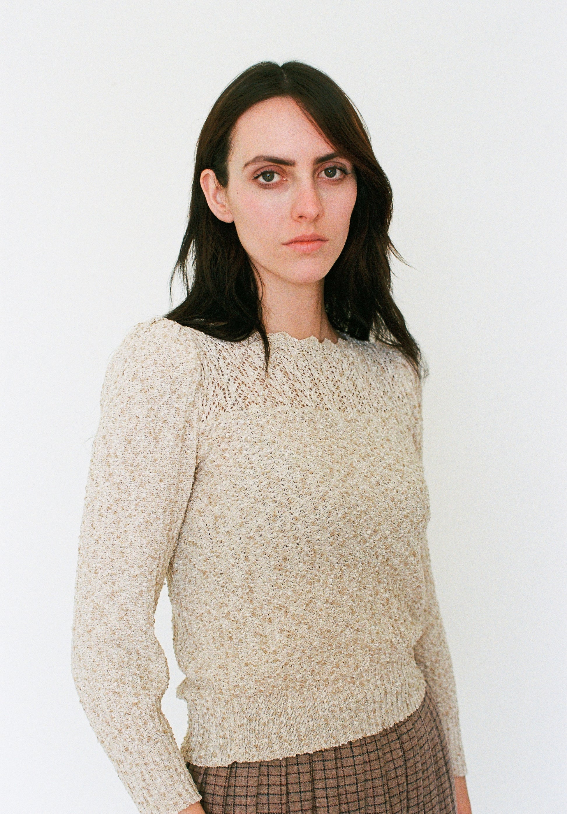 Woman wearing a beige sweater against a white background