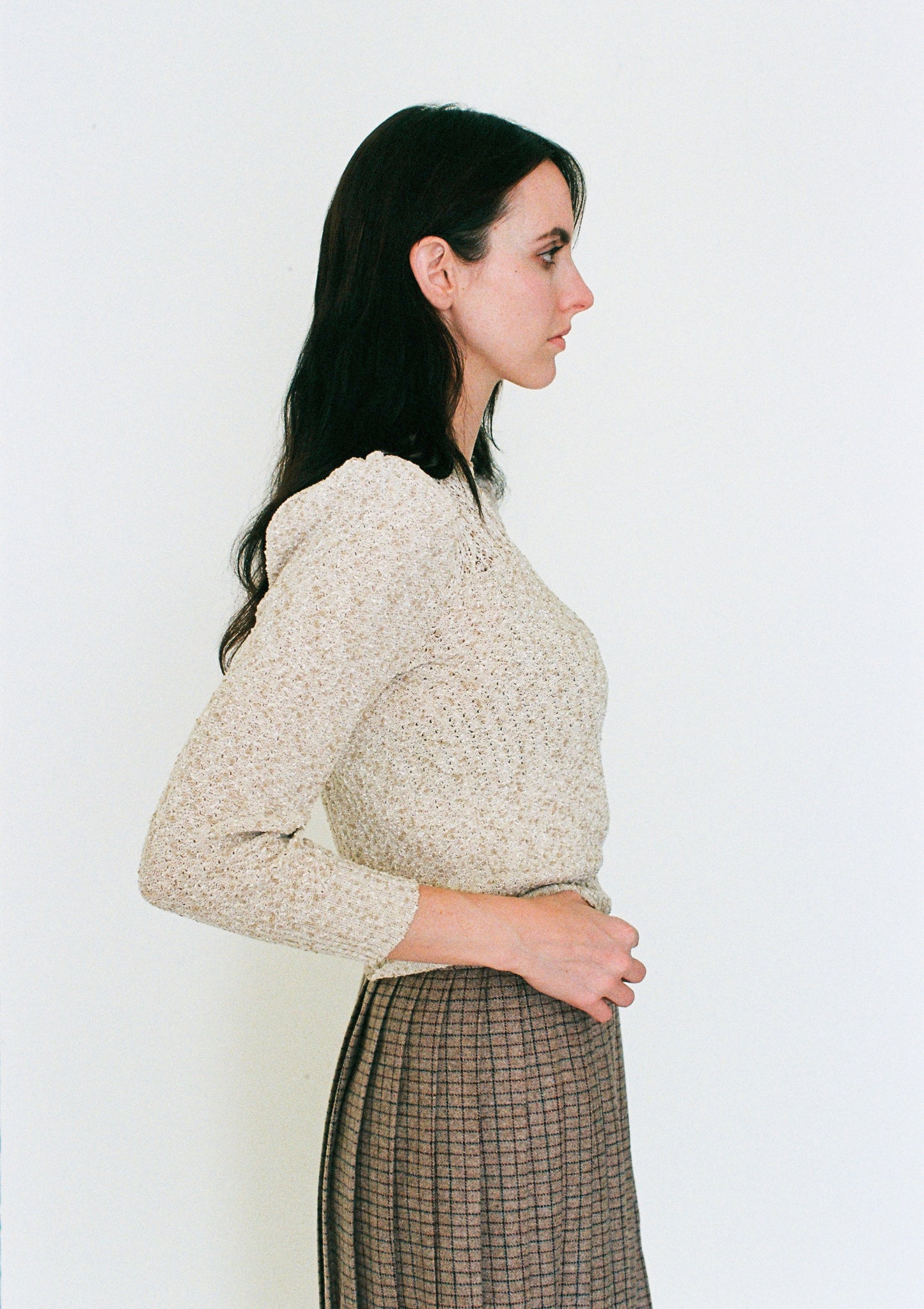 Woman wearing a beige knitted sweater against a white background
