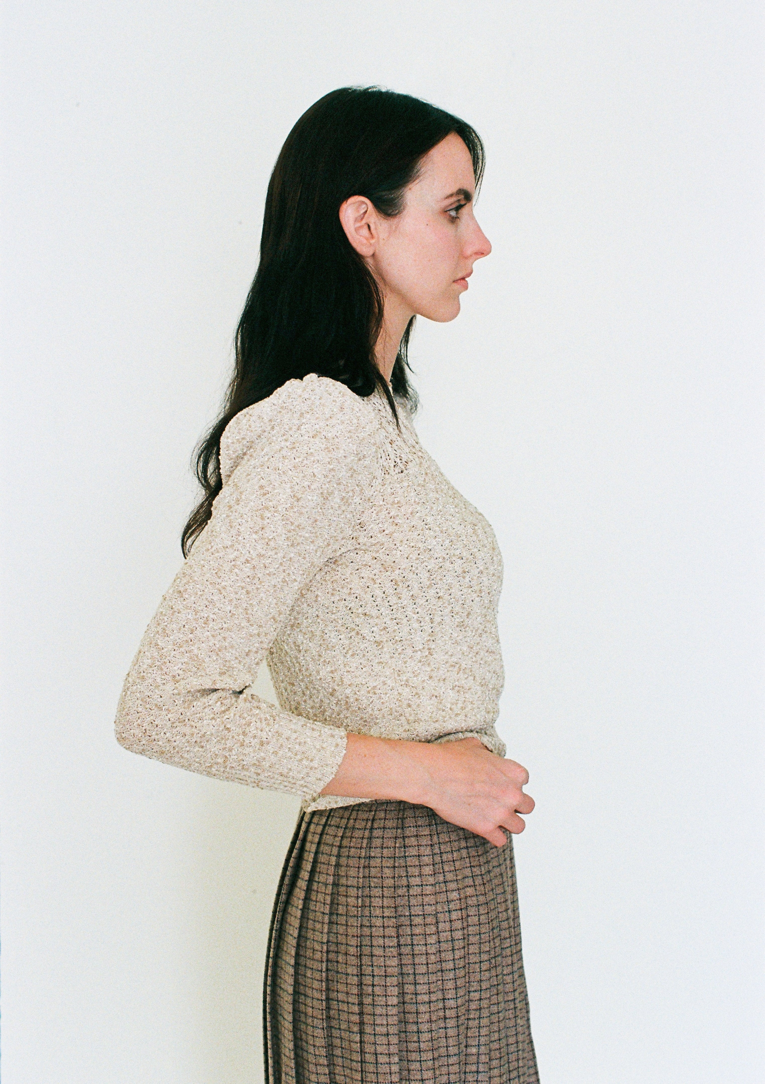 Woman wearing a beige knitted sweater against a white background