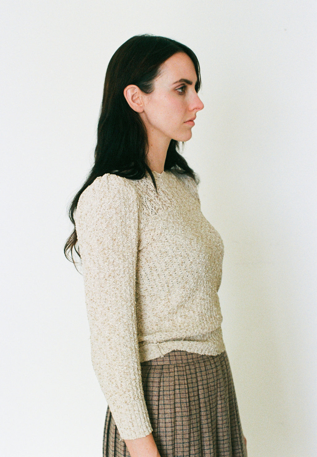 Woman wearing a textured beige sweater against a plain background