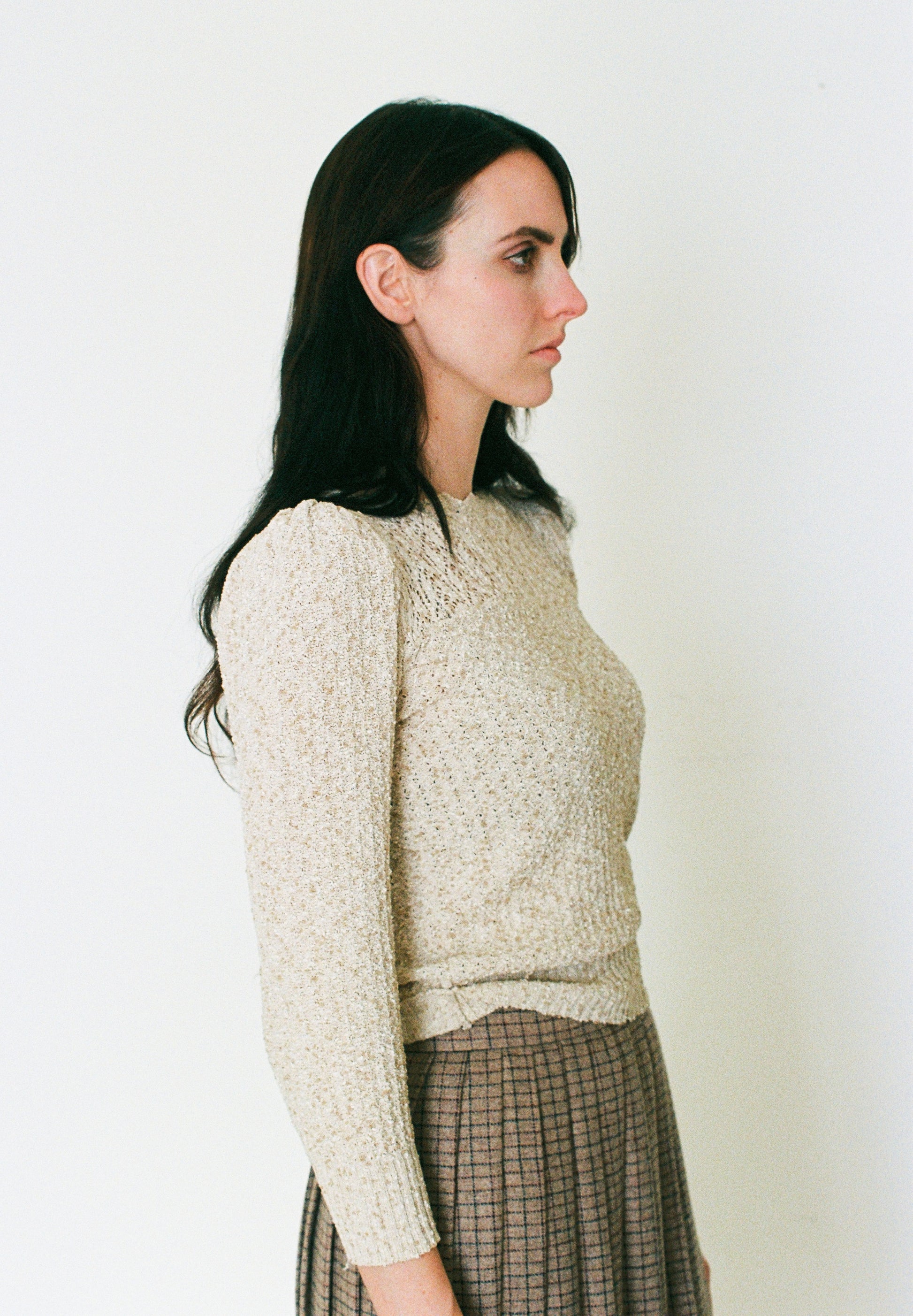 Woman wearing a textured beige sweater against a plain background