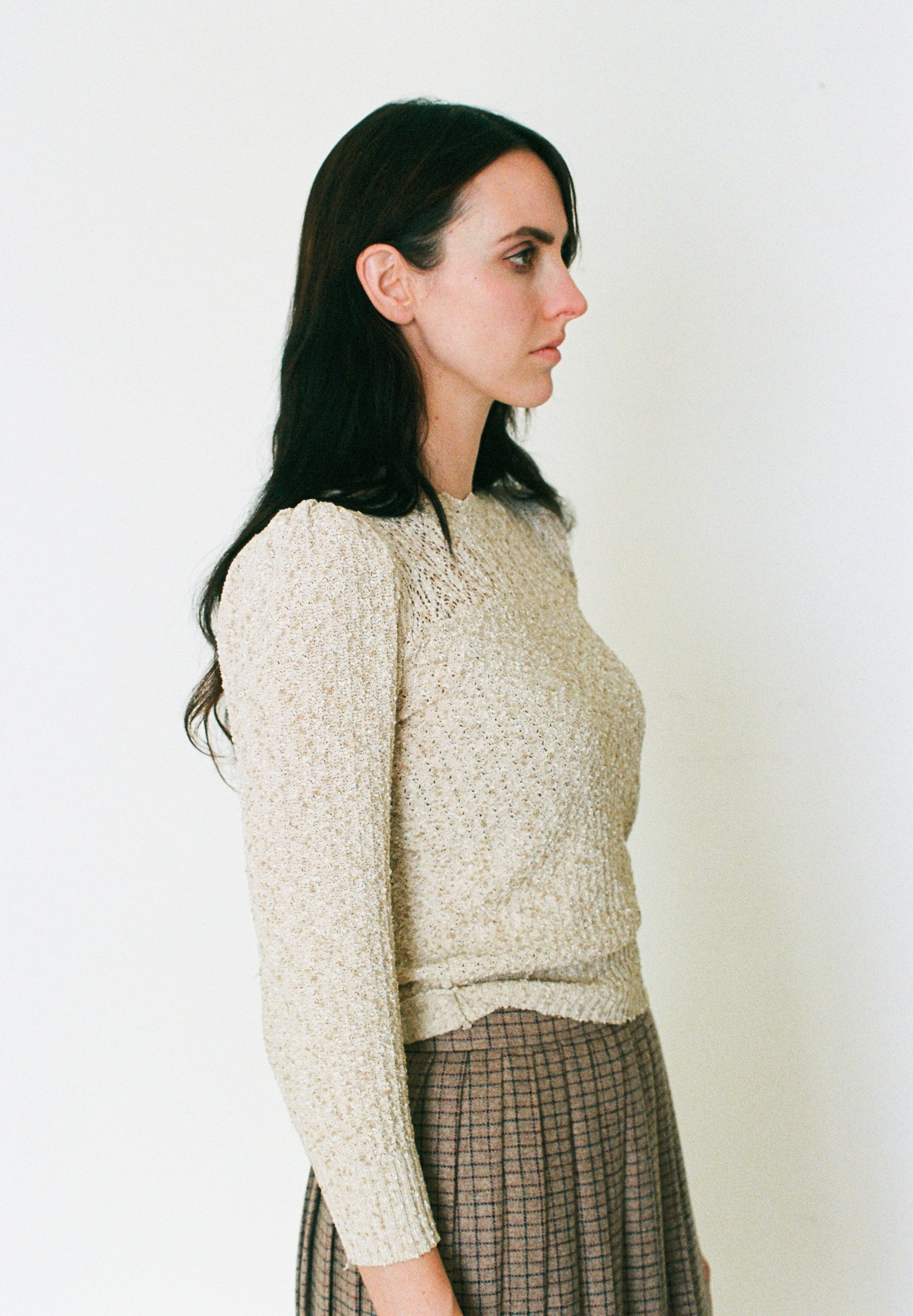 Woman wearing a textured beige sweater against a plain background