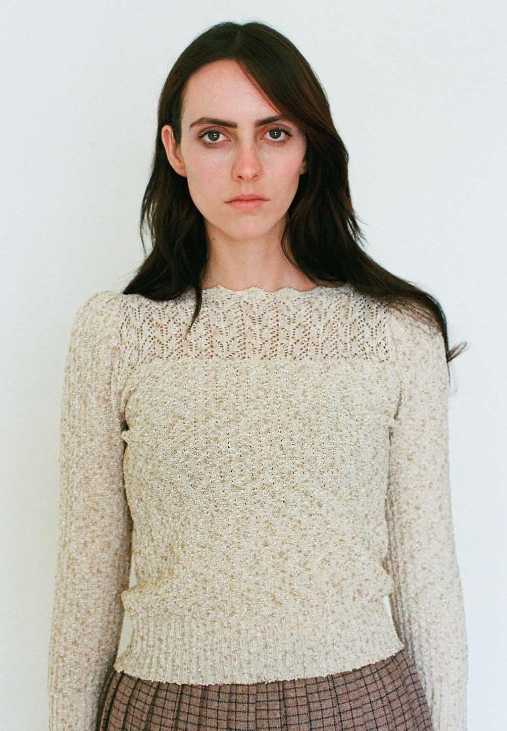 Woman wearing a beige knitted sweater against a plain background