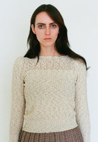 Woman wearing a beige knitted sweater against a plain background