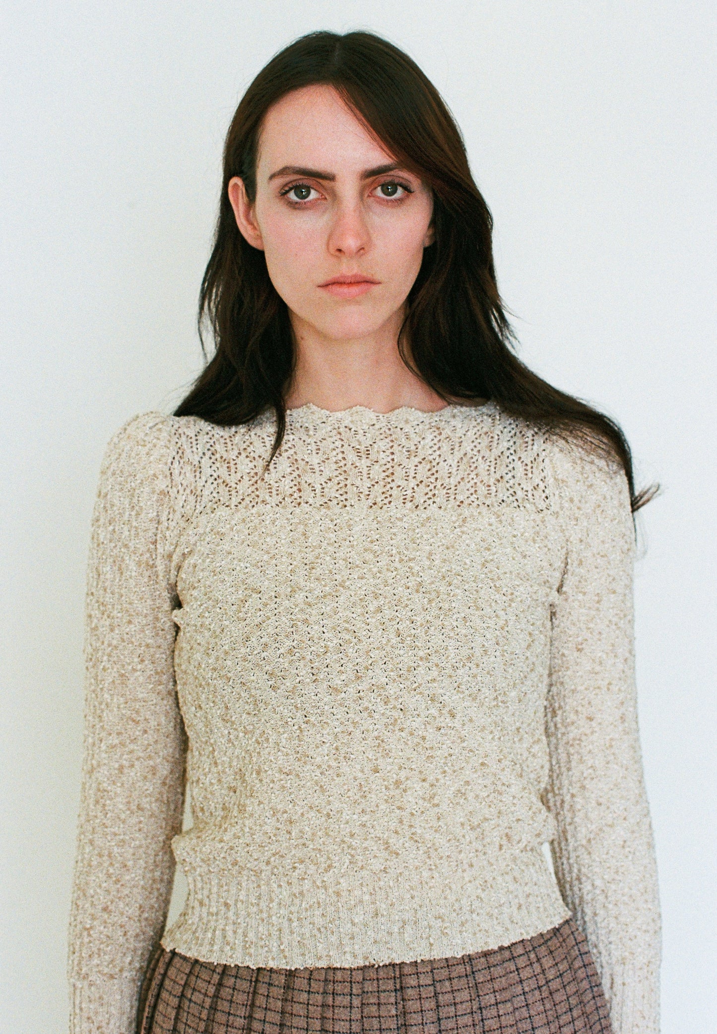 Woman wearing a beige knitted sweater against a plain background