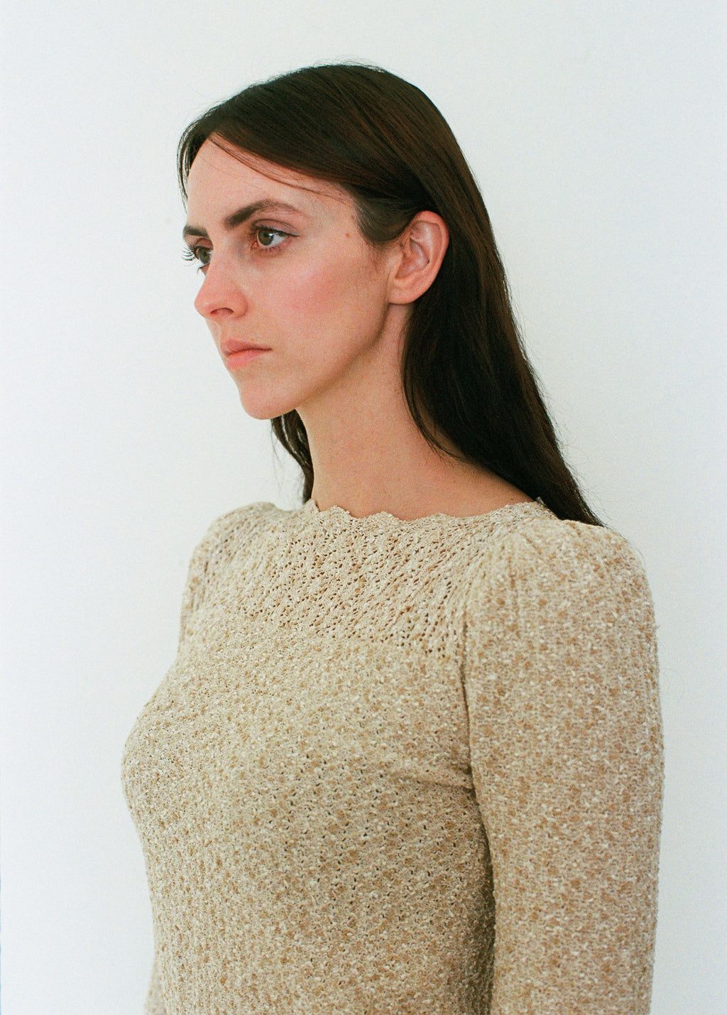 Woman wearing a beige textured sweater against a white background