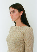 Woman wearing a beige textured sweater against a white background