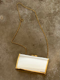 Gold and silver clutch bag with chain strap on a textured surface