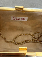 Gold chain necklace inside a gold jewelry box with 'Made for Delill in Hong Kong' label.