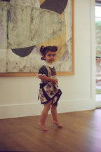 Young girl in a patterned dress standing in front of an abstract painting