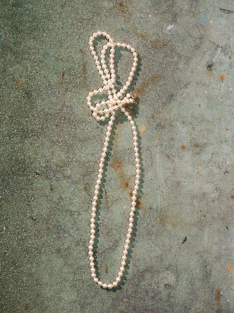 Pearl necklace on a textured green surface