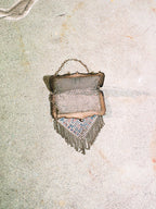 Vintage-style handbag with fringe on a textured surface