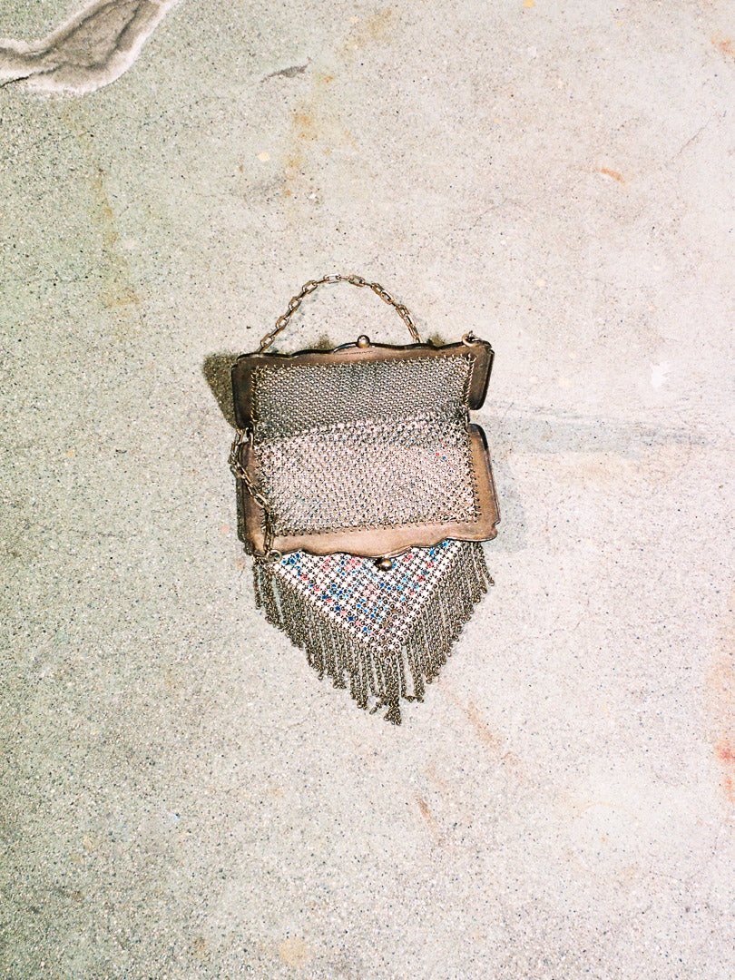 Vintage-style handbag with fringe on a textured surface
