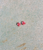 Two pink earrings on a textured beige surface