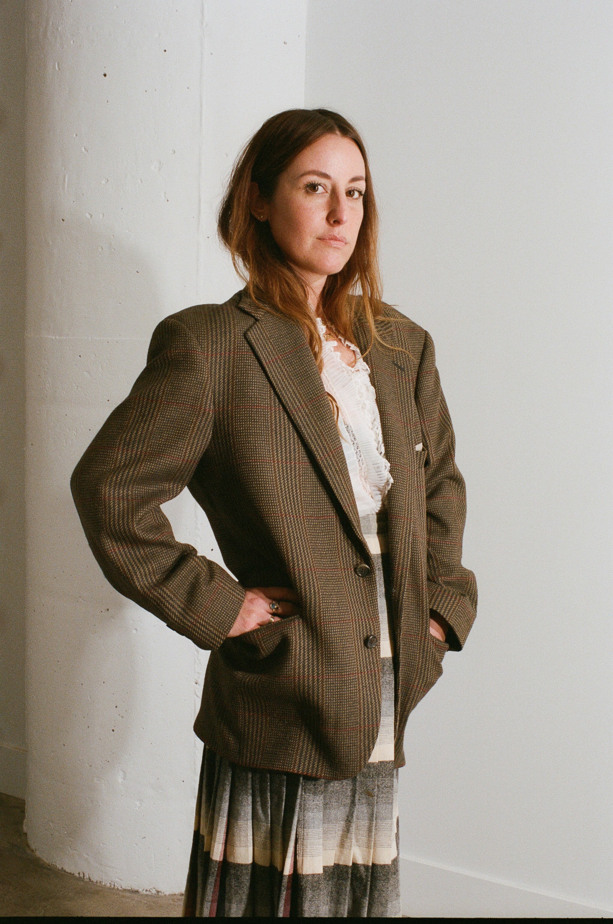 Woman wearing a brown blazer against a white wall