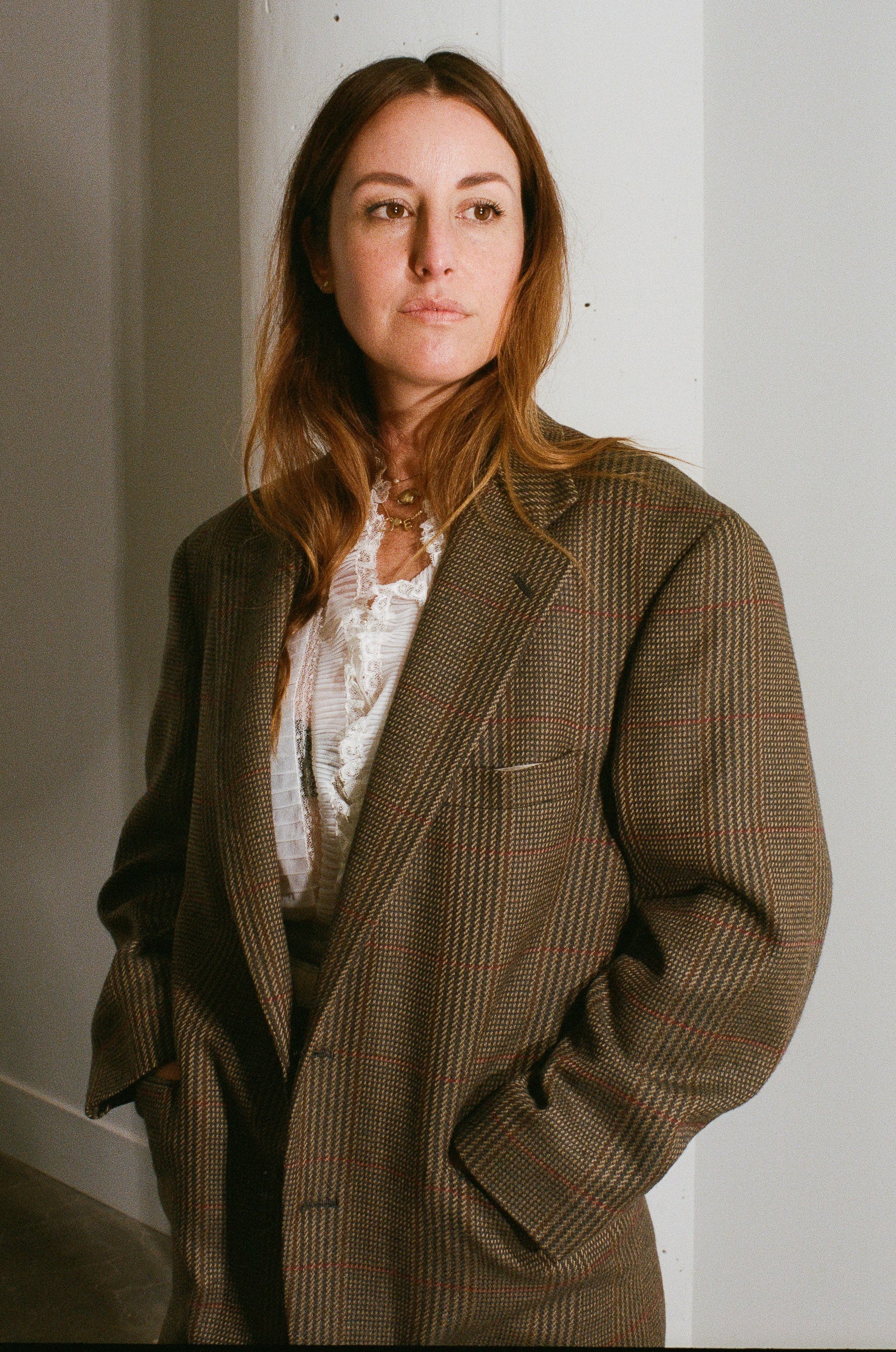 Woman wearing a brown checkered coat against a white wall