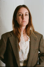 Woman wearing a brown blazer over a white blouse against a plain background