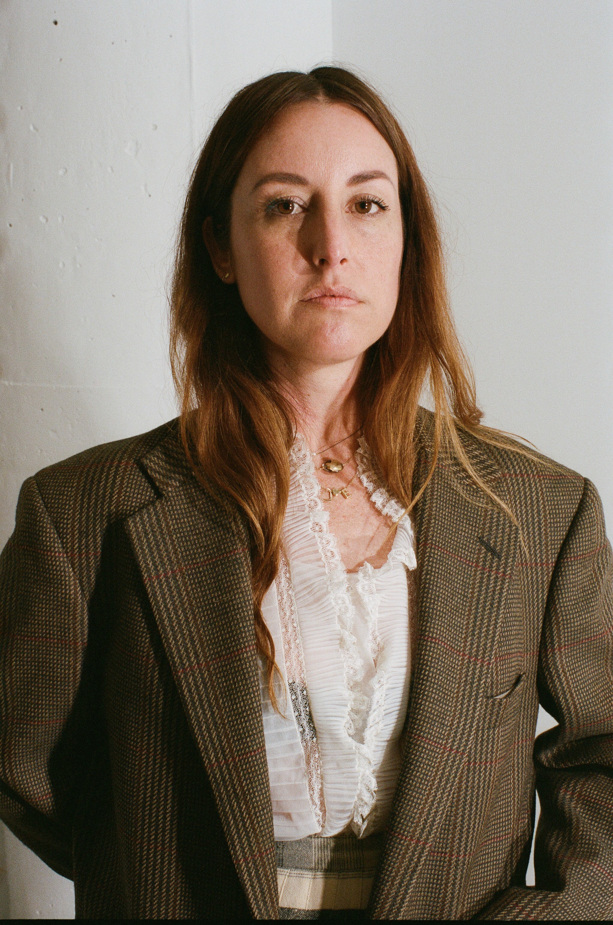 Woman wearing a brown blazer over a white blouse against a plain background