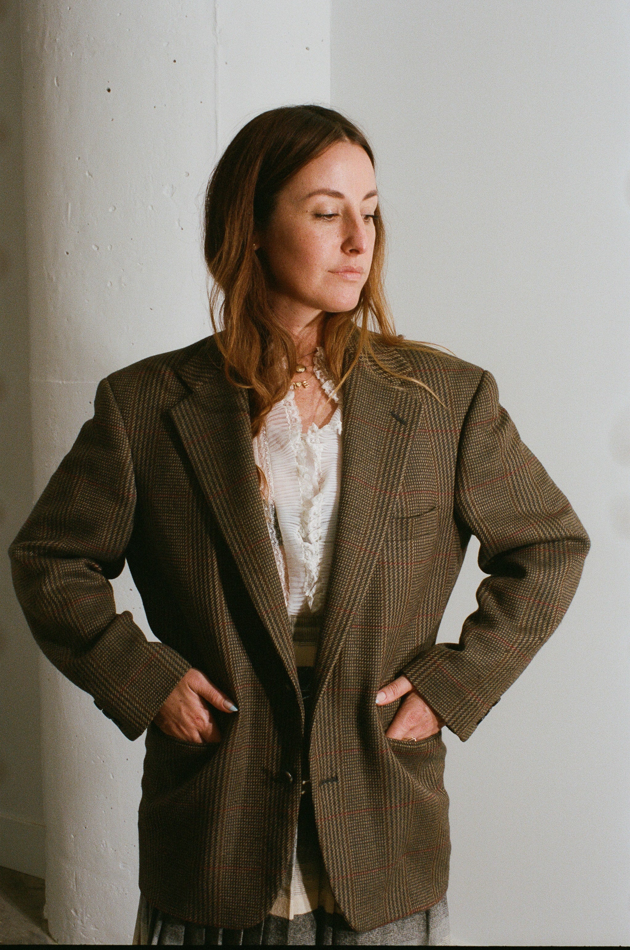 Woman wearing a brown pinstripe coat against a white wall