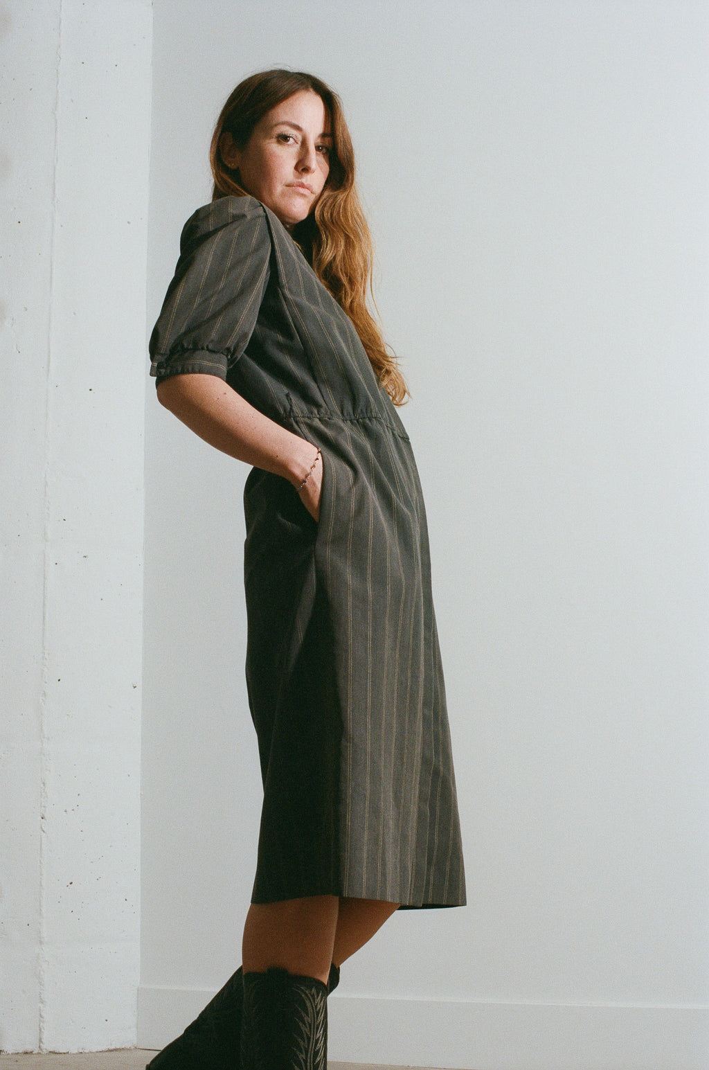 Woman wearing a long green dress against a white wall