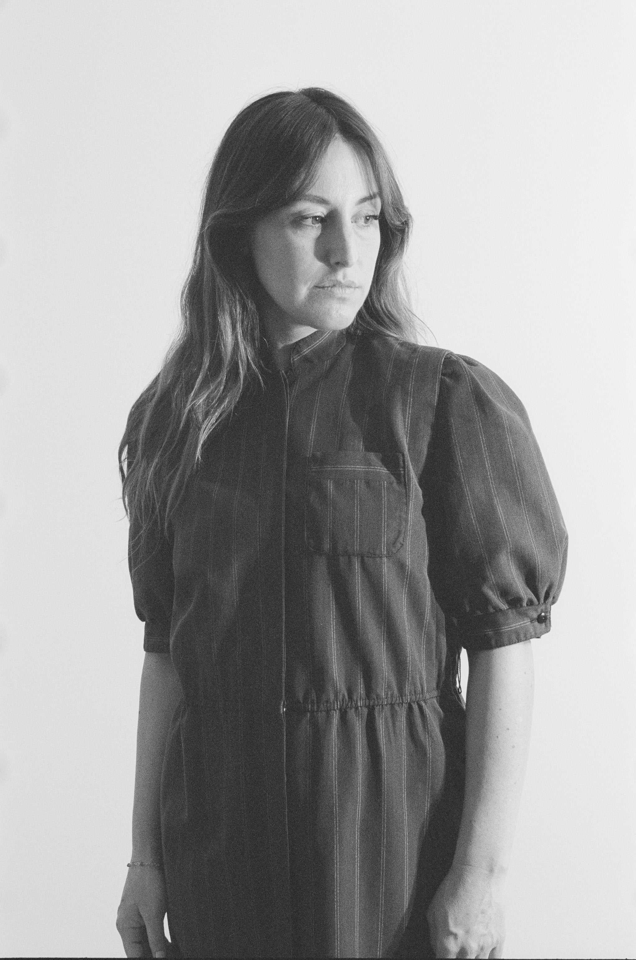 Black and white photo of a person wearing a dark dress against a plain background