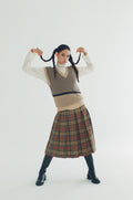 Woman wearing a patterned vest and plaid skirt on a white background